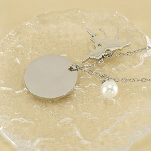Detail of silver unicorn set with deer charm, round tag and pearl on glass tray