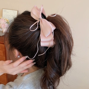 Detail of pink silk bow hairclip with rhinestone center worn on a ponytail