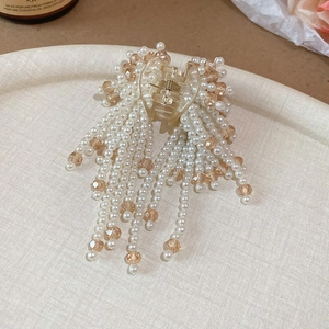 Detail of elegant hair claw clip with white faux pearls and amber beads tassel