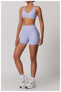 Dettaglio dei pantaloncini da yoga lilla a vita alta e del reggiseno sportivo in tessuto elastico