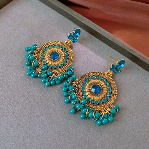 Detail of vintage gold earrings with blue gemstones and turquoise fringe beads