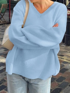 Detail view of light blue V-neck knit sweater with ribbed cuffs in a casual outdoor setting