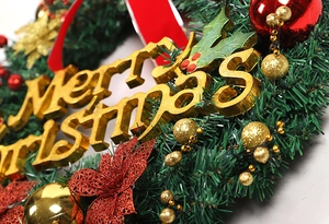 Detail of a Christmas wreath featuring golden Merry Christmas text and red ornaments