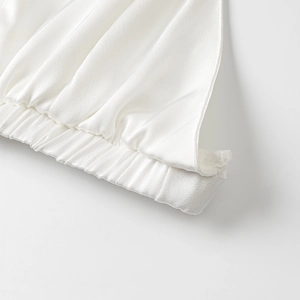 Détail du tissu satiné blanc montrant l'ourlet élastique avec plis et texture lisse