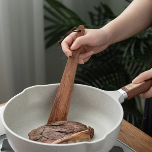 Spatule en bois d'acacia pour poêles antiadhésives cuisant un steak dans une poêle