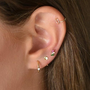 Close-up of gold 925 silver stud earrings with crystals and colorful gems on model ear