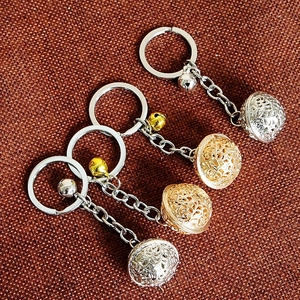 Detailed view of hollow sphere pendants and bells on gold and silver keychains