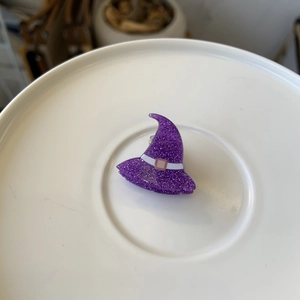 Sparkly purple witch hat hair clip with glitter finish on a white plate for Halloween
