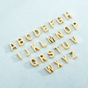 Set of 26 golden stainless steel letter pendants A-Z arranged on a blue textured background