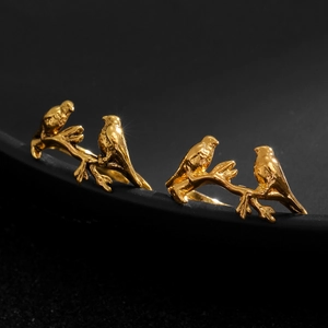 Close-up of golden hummingbird rings featuring birds perched on intricate metal branches