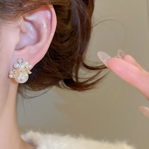 Macro shot of elegant firework pearl earrings with zircon inlay worn by a female model