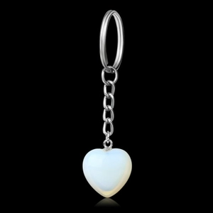 Detail view of heart-shaped opal stone pendant with silver metal chain on black background