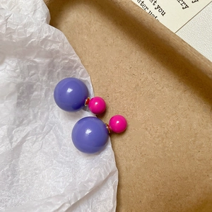 Detailed shot of two-tone purple and pink spherical earrings on a rustic paper background
