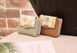 Détail de petits portefeuilles en cuir PU vert et marron avec motifs floraux et fermoir métal