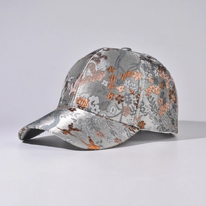 Detail of silver baseball cap featuring golden jacquard floral pattern and butterfly embroidery