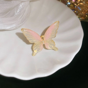Close-up of pink gradient butterfly ring with pearls on a decorative ceramic shell plate