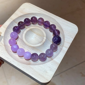 Macro shot of natural amethyst beaded bracelet with purple gradients on a wooden tray