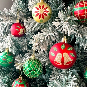 Detailed view of painted Christmas ball ornaments with glitter on a snowy pine tree