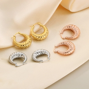 Detailed view of oval textured hoop earrings in gold, rose gold and silver on satin