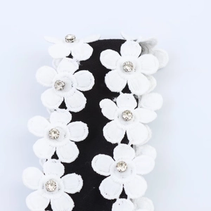 Detailed macro view of white floral embroidery and sparkling rhinestones on black fabric