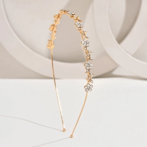 Detail of a golden metal headband featuring sparkling rhinestone flower decorations
