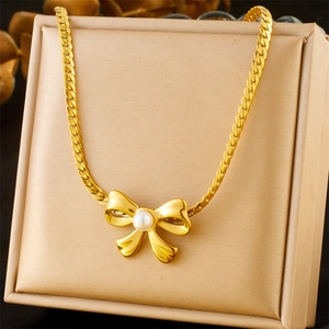 Elegant gold bow necklace with white pearl center pendant on a jewelry display box