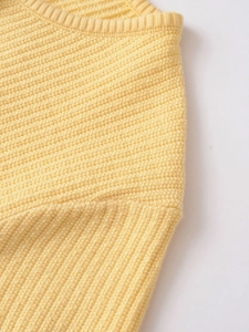 Macro shot of yellow knit cardigan showing ribbed neck and waffle texture fabric