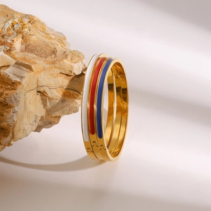 Trois bracelets en émail blanc rouge et bleu avec bordure dorée sur un rocher