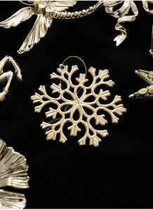 Macro di ciondoli a fiocco di neve e stella dorati su sfondo di velluto nero