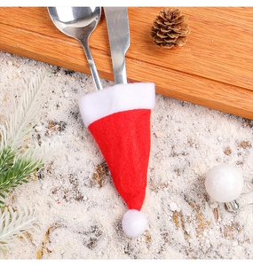 Close-up of red and white Christmas hat cutlery holders on a festive snowy wooden table