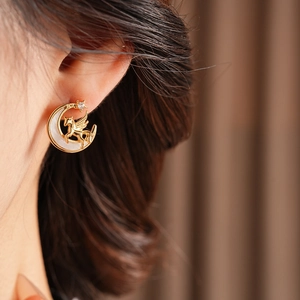 Close-up of a vintage crescent moon and pegasus earring with zircon on model