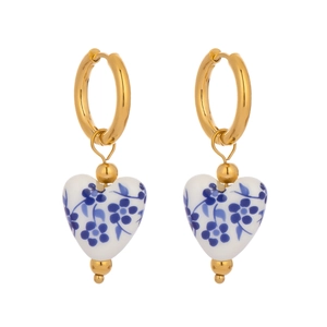 Detail of vintage heart-shaped blue and white porcelain earrings with golden hoops