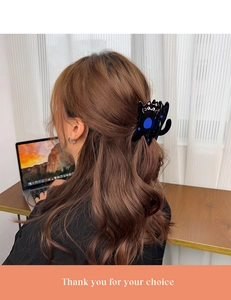 Detailed view of a cute black cat acetate hair claw clip worn on a woman's ponytail