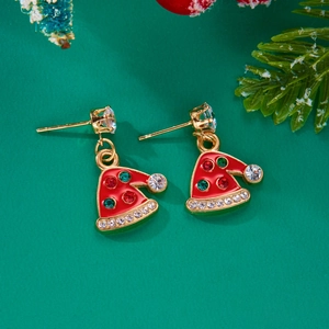 Detailed macro of festive red Santa hat earrings with colorful crystals on green backdrop