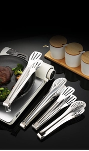 Close-up of polished stainless steel food tongs for steak and BBQ on a kitchen counter