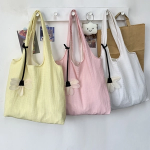 Detail of vibrant pleated canvas tote bags in yellow, pink and white with daisy charms
