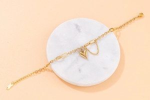 Detail of a gold heart pendant bracelet on marble base with fine chain accent