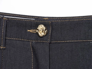 Gros plan détaillé d'un bouton en métal doré et de coutures brunes sur denim foncé