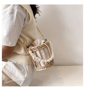 Straw bucket bag detail featuring pearl handle and gold chain strap on model