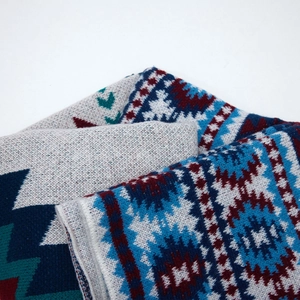 Close-up of ethnic geometric pattern weaving on soft knit shawl with navy and wine accents
