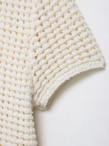 Gros plan du cardigan en maille blanc crème montrant la texture du crochet