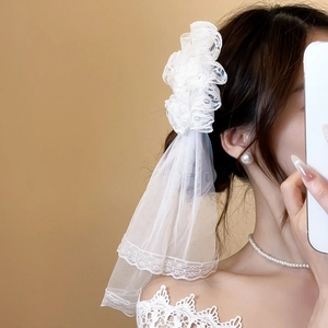 Detailed white lace flower hair clip with layered tulle veil for elegant bridal styling