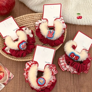 Detailed view of red plush hair scrunchies with cute cartoon charms on display cards
