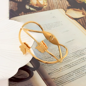 Detail of golden butterfly open bangle featuring fine spring clasp on vintage prop book