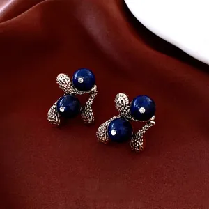 Vintage gold resin teardrop earrings with deep blue beads and silk background