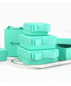 Detailed stacked dark teal jewelry gift boxes with satin bows on a marble tray