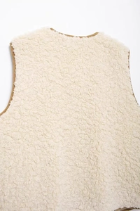 Detailed close-up of fuzzy lamb wool vest material with brown trim piping