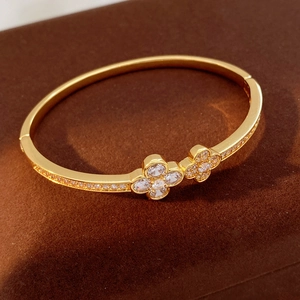 Macro shot of gold clover bangle with sparkling zircon pavé detail and glossy finish