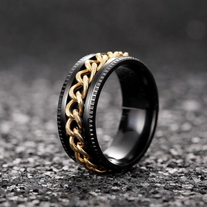 Macro view of rotating black stainless steel ring with golden Cuban chain inlay details