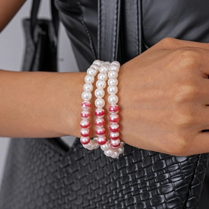 Détail d'un bracelet à trois couches de perles nacrées avec des perles à texture marbrée rouge